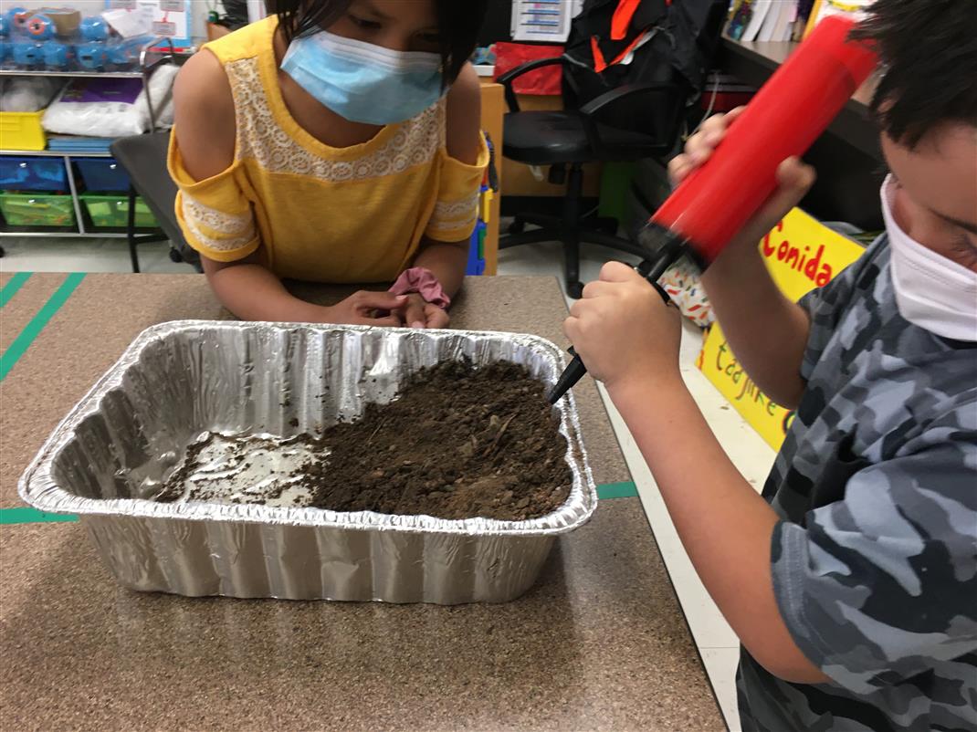 Students using a balloon pump to recreate wind erosion